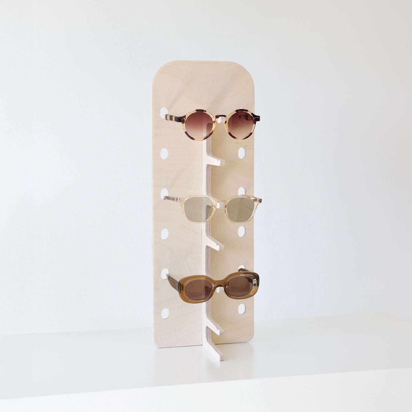 Vue de côté du présentoir JAMIE avec lunettes soigneusement disposées sur ses supports en bois.