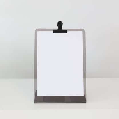 Présentoir en acrylique JOHN A4 équipé d’une pince noire, parfait pour menus ou programmes dans un espace d’accueil.