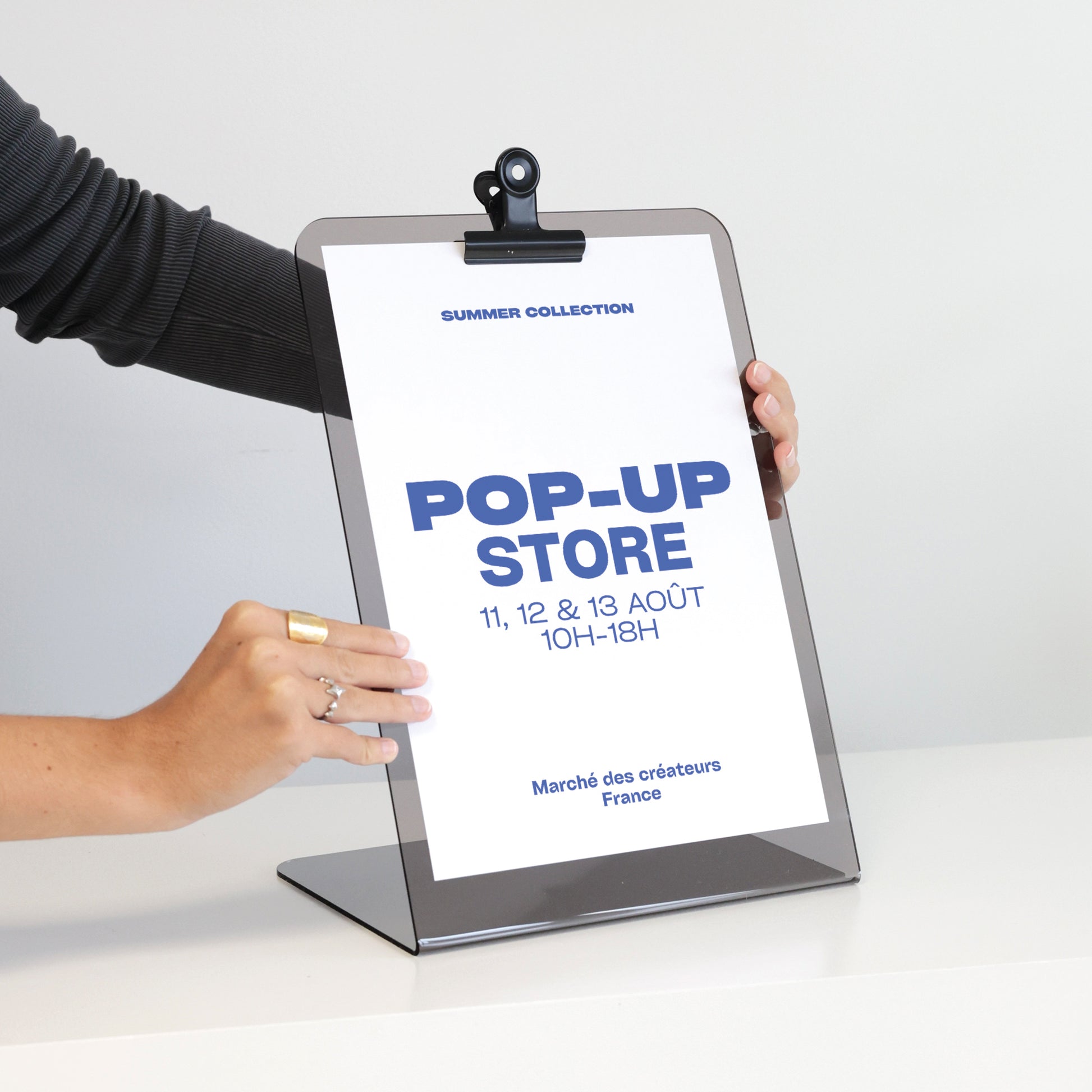 Présentoir JOHN en acrylique présentant une affiche au format A4 avec une pince métallique noire pour la maintenir