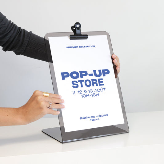 Présentoir JOHN en acrylique présentant une affiche au format A4 avec une pince métallique noire pour la maintenir