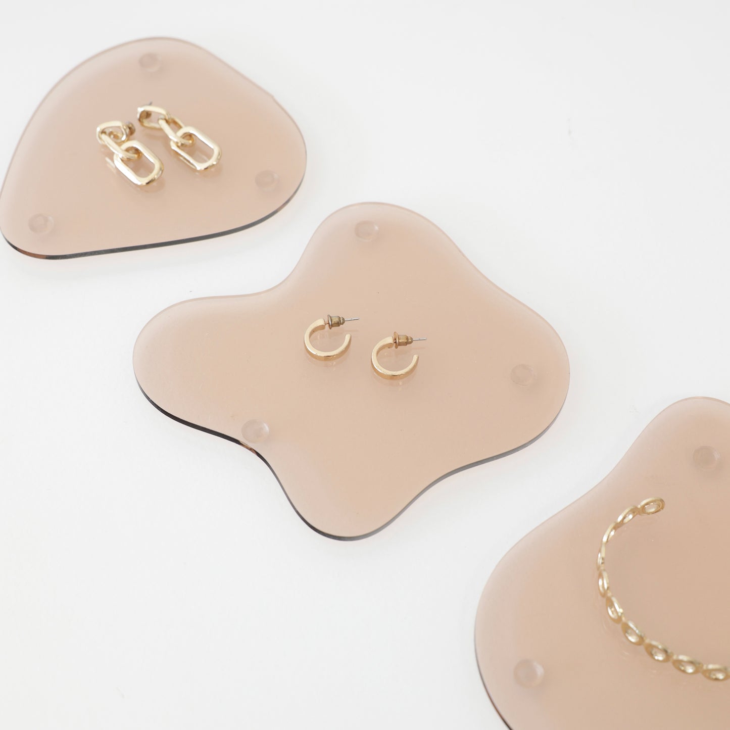 Plateaux en acrylique rose fumé transparents découpés au laser, utilisé pour une mise en scène de bijoux