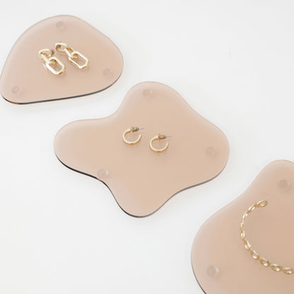 Plateaux en acrylique rose fumé transparents découpés au laser, utilisé pour une mise en scène de bijoux