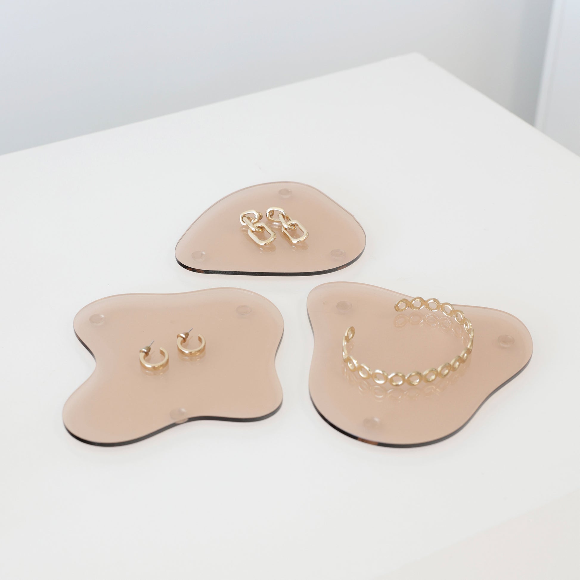 Ensemble de plateaux en acrylique aux formes organiques, disposés pour un shooting photo