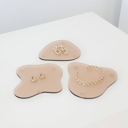 Ensemble de plateaux en acrylique aux formes organiques, disposés pour un shooting photo