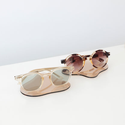 Plateaux en acrylique transparent aux lignes fluides, présentant des lunettes dans une boutique
