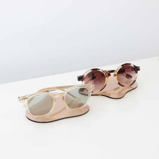 Plateaux en acrylique transparent aux lignes fluides, présentant des lunettes dans une boutique