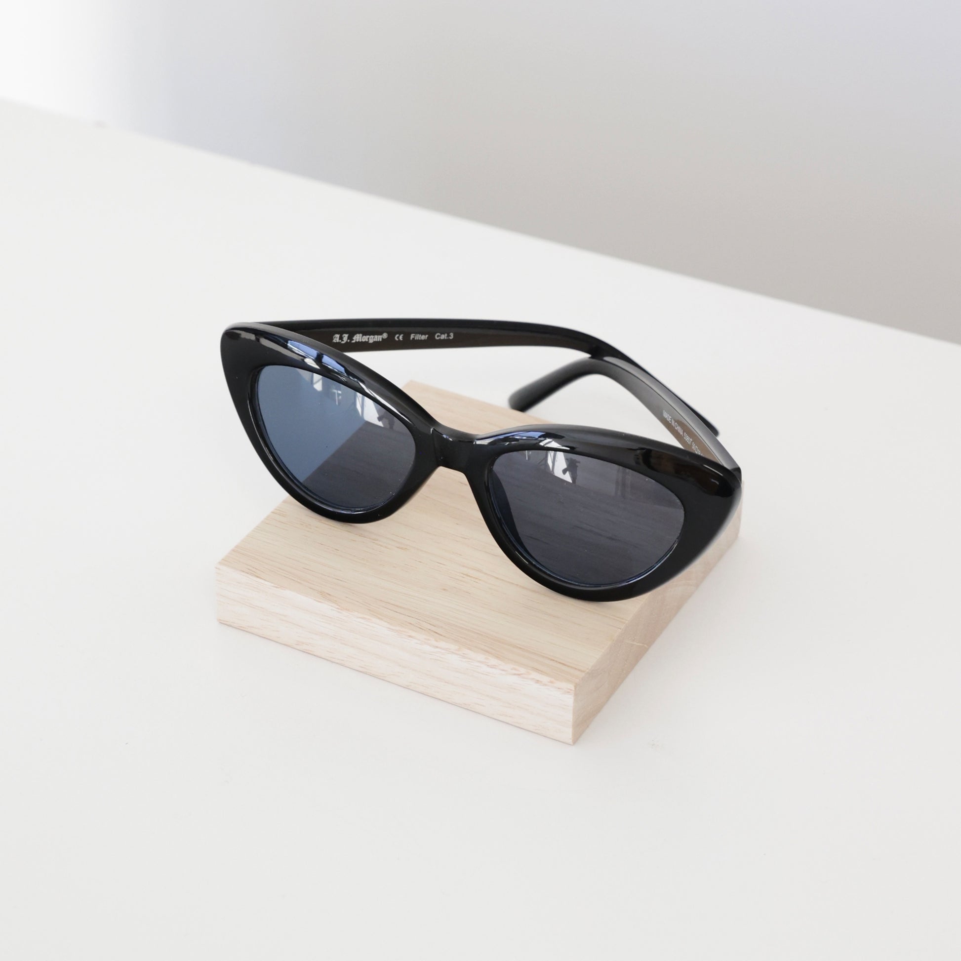 Plateau en bois carré de 10x10cm, présentant une paire de lunettes de soleil en boutique