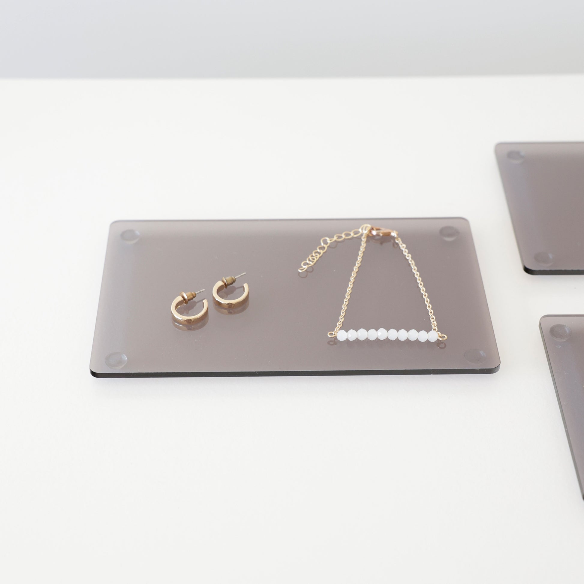 Plateau gris en acrylique transparent, présentant des bijoux en boutique