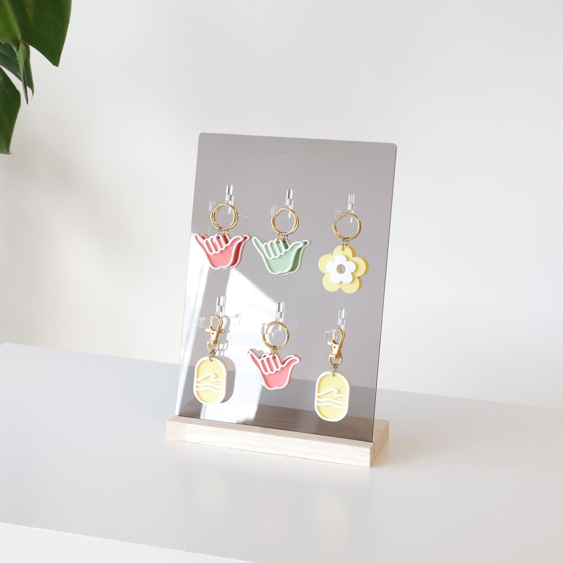 Présentoir en acrylique gris fumé et bois naturel, pour présenter des porte-clés sur un comptoir de magasin